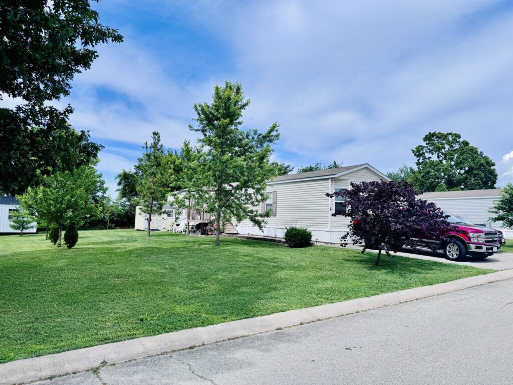Home with a large green lawn at Cedar Glen Mobile Home Park in Aurora, MO